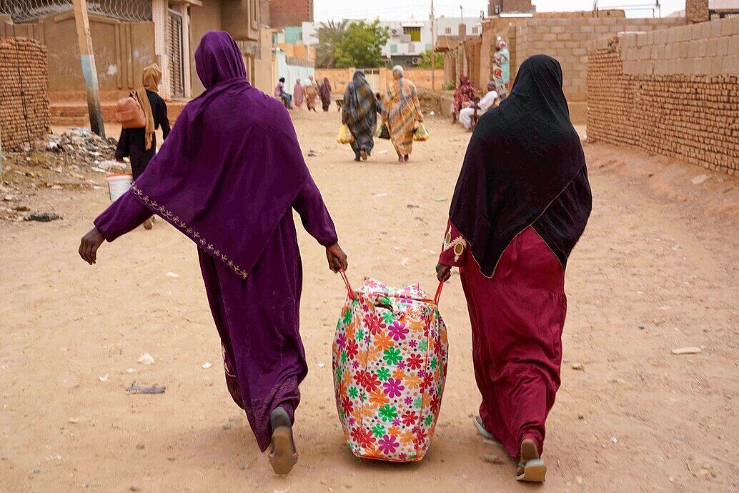 Dos mujeres transportan una bolsa con pertenencias por las calles de Omdurman