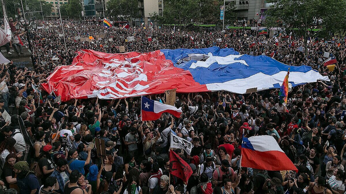 Manifestantes llevan una bandera chilena gigante en una manifestación masiva