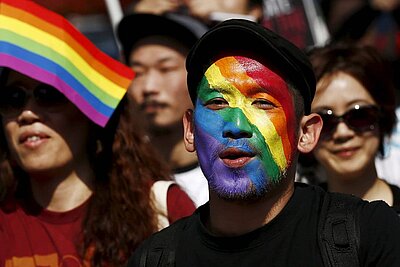 Hombre con la cara pintada con los colores del arco iris
