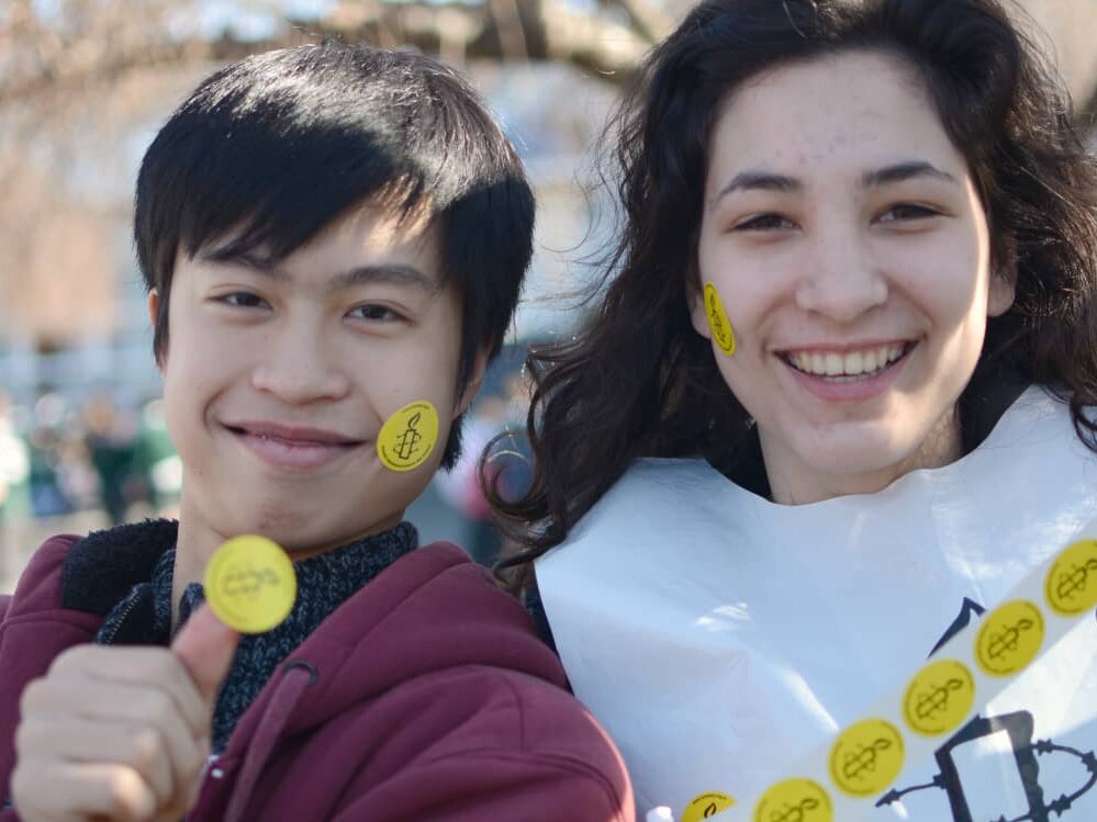 Dos jóvenes con pegatinas de Amnistía Internacional