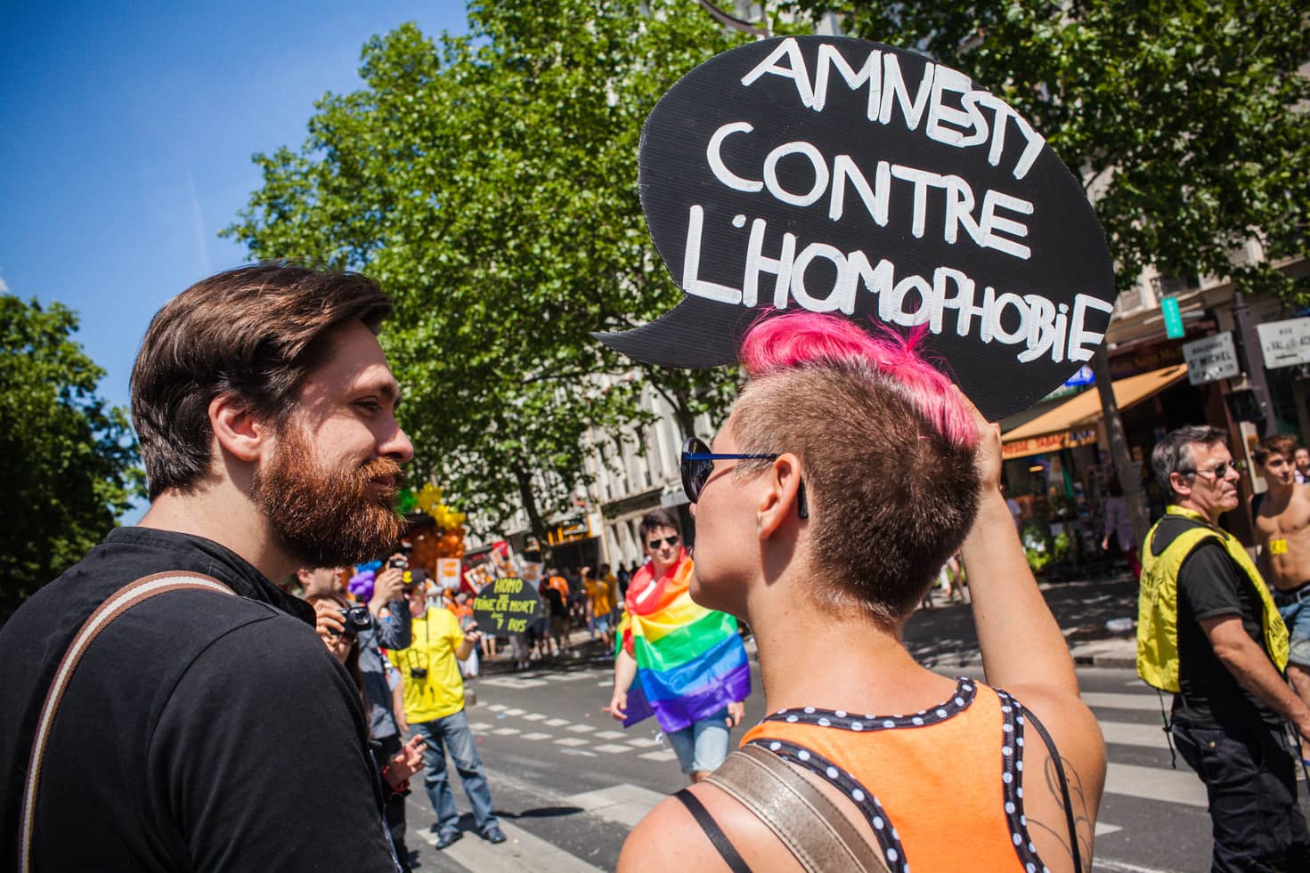 Dos personas en la Marcha del Orgullo en París portan una pancarta que pone "Amnesty contre l'homophobie"
