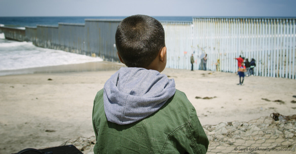 Niño mirando hacia la valla de la frontera