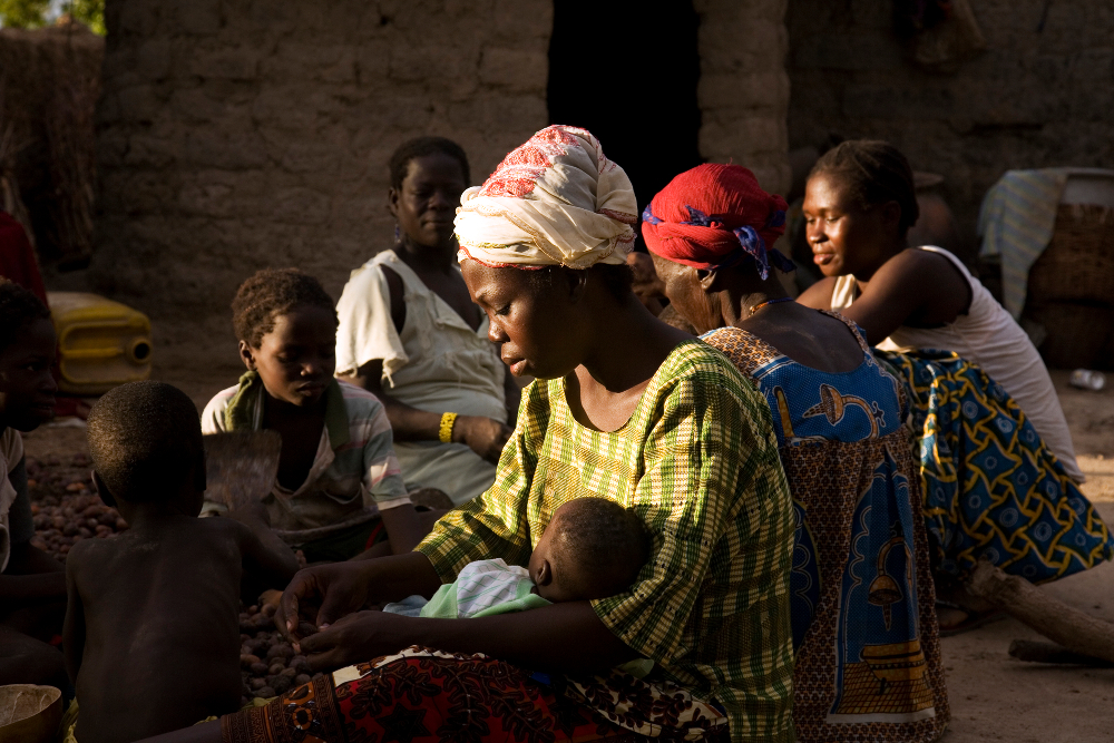 Patricia, de 29 años (que va de verde) y otra mujer en la familia partiendo nueces rodeadas de sus hijos e hijas. © Anna Kari