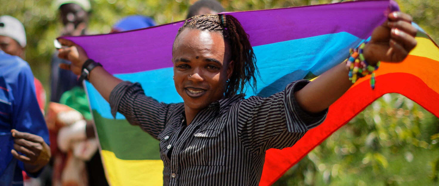 Refugiado LGBT con una bandera arcoiris en los hombros
