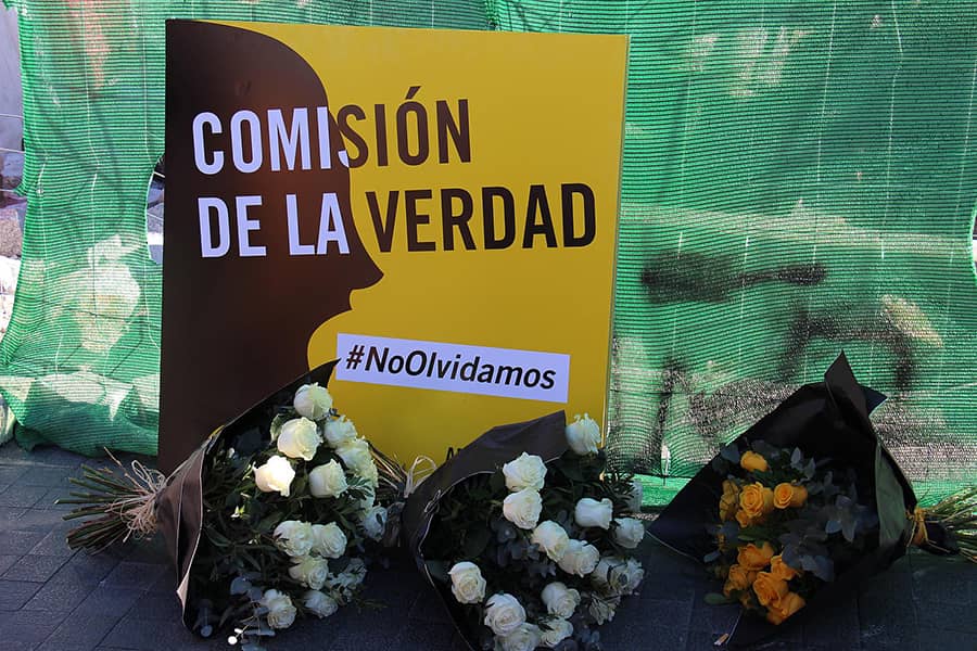 Ramos de flores y un cartel en el que Amnistía Internacional pide al gobierno una Comisión de la Verdad