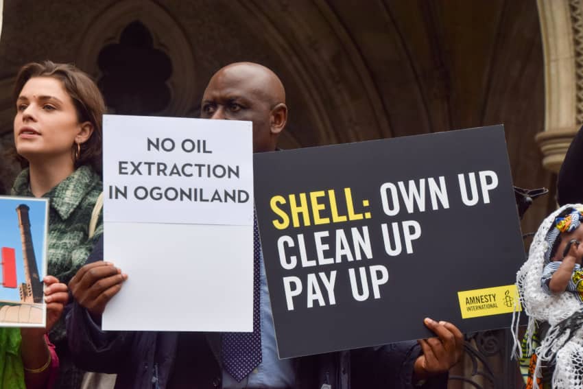 Manifestantes sostienen pancartas de Amnistía Internacional pidiendo que Shell limpie y repare los daños por contaminación petrolera en Nigeria.