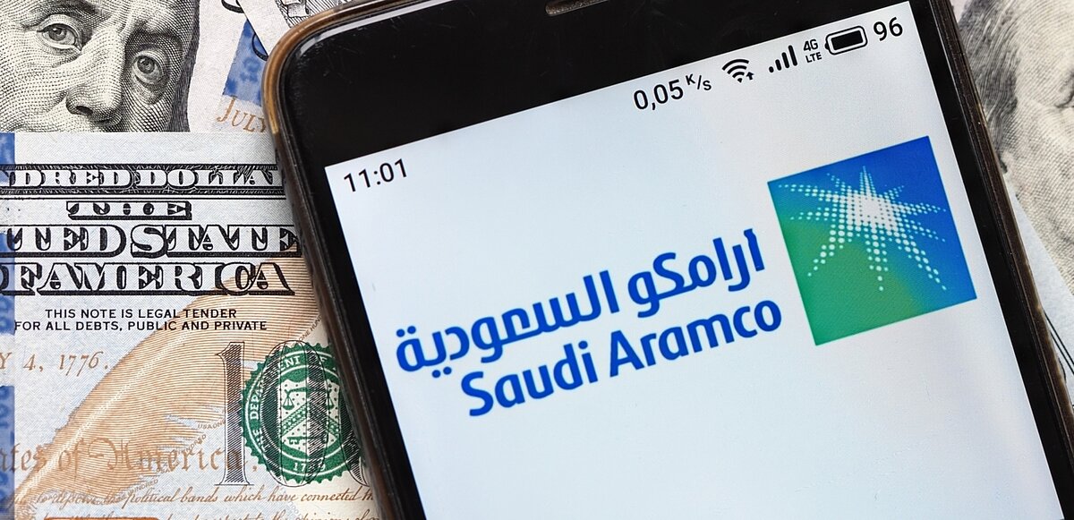 Montaje fotográfico con billetes de dólares y una imagen de Aramco