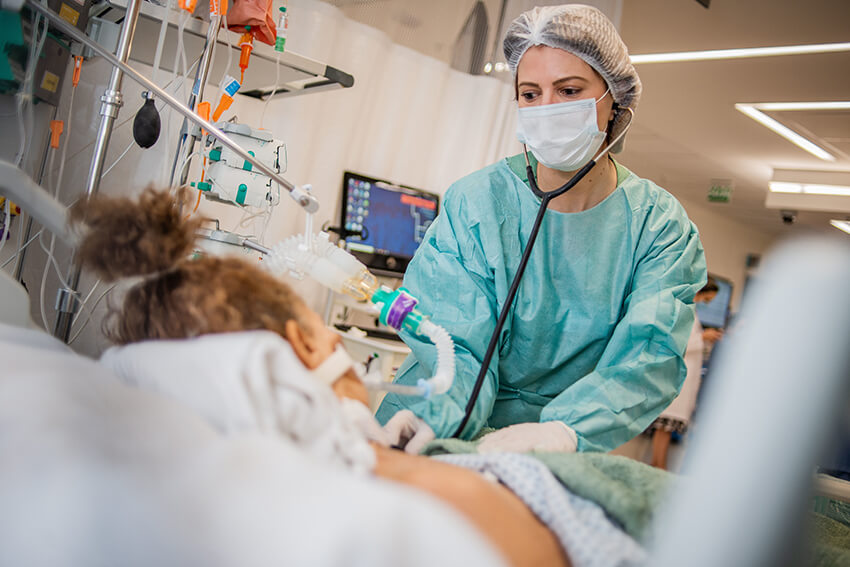 Una enfermera atiende a una paciente en la cama de un hospital