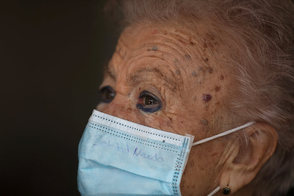 Soledad Nevado, de 85 años, usa una mascarilla protectora con su nombre escrito en ella mientras espera a lanzar globos durante el homenaje a las...