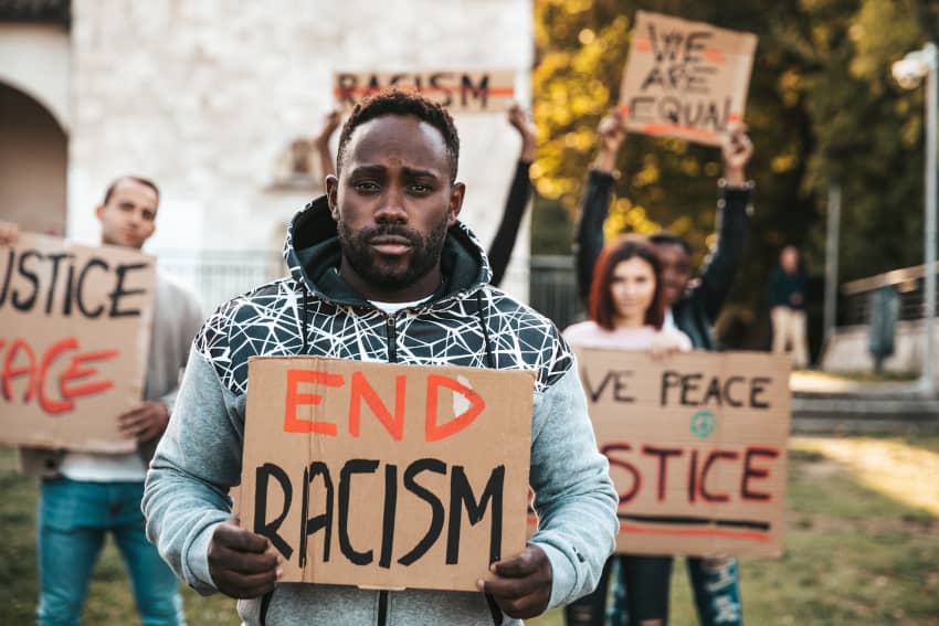 Un activista sostiene un cartel que pone: "pongamos fin al racismo". Rechacemos las frases racistas