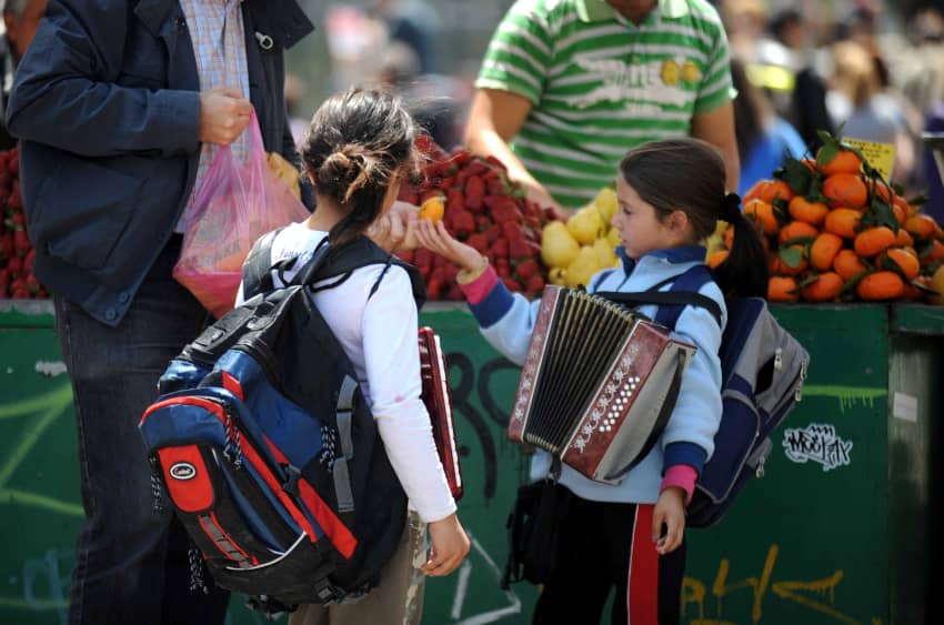 Dos niñas tocan el acordeón para que los turistas les den algo de dinero