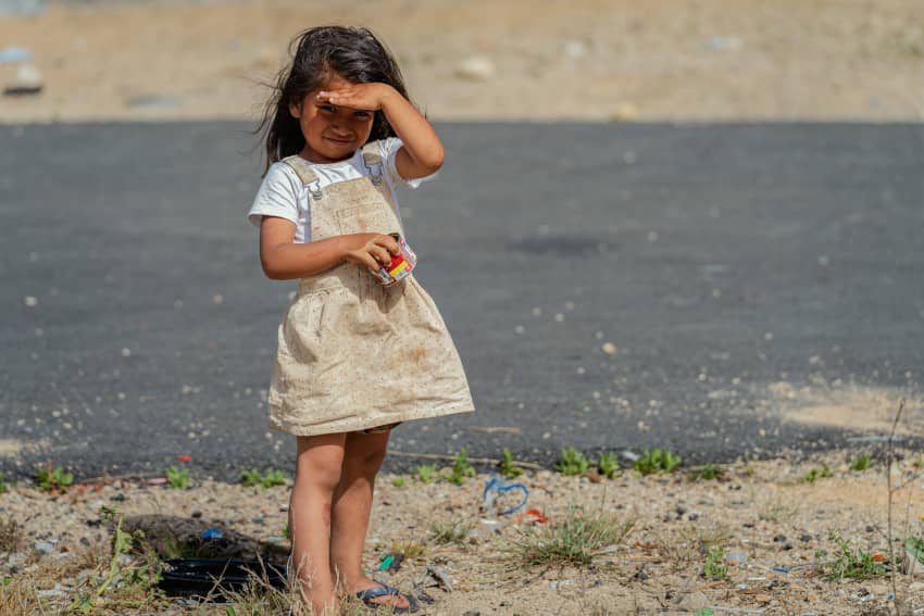 Niña permanece sola en un campamento de desplazados en Beirut bajo el sol mientras espera junto a las tiendas de campaña.
