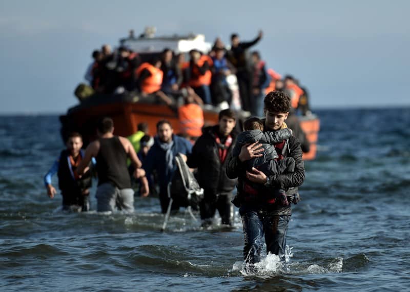 Personas refugiadas desembarcando en una playa