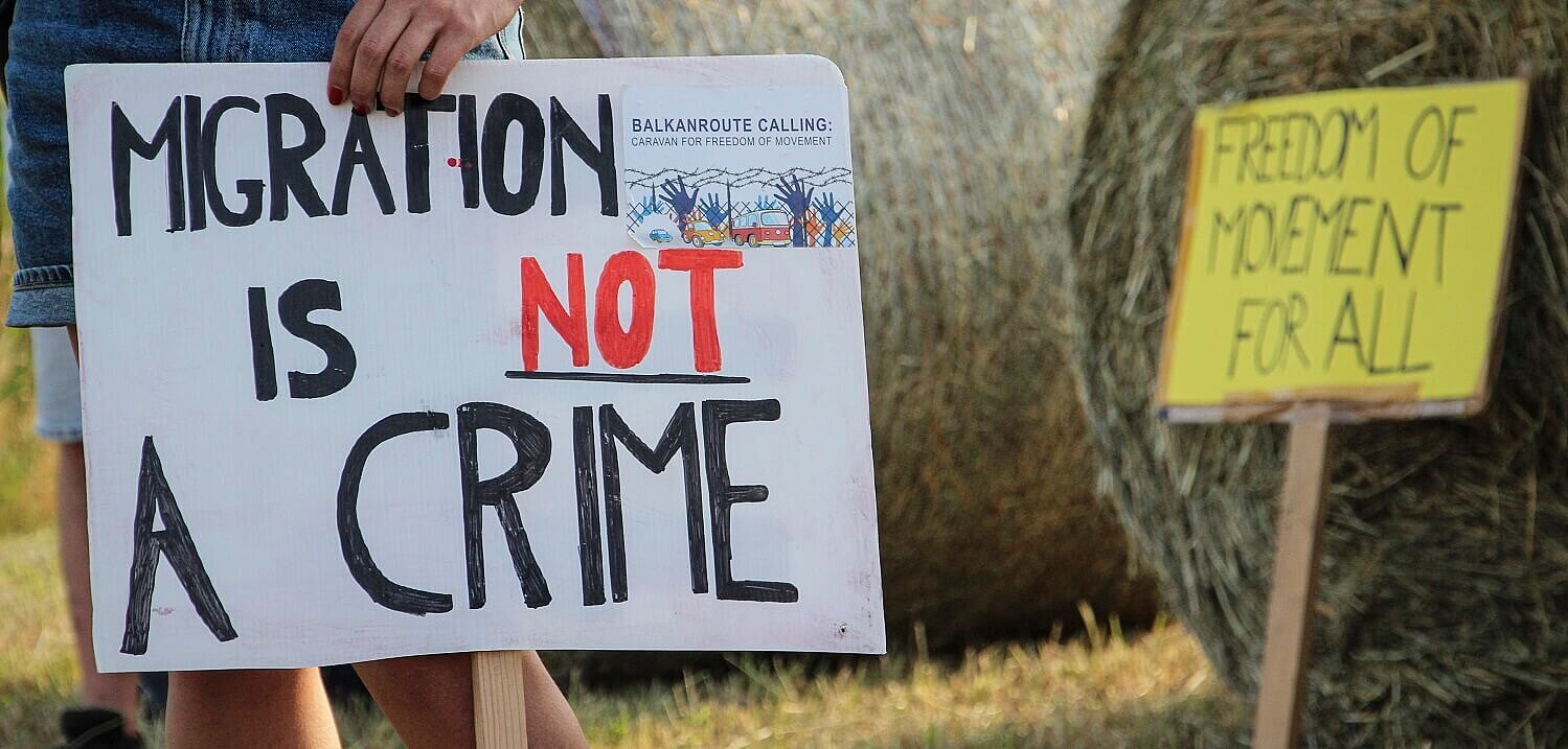 Una mujer sostiene una pancarta durante una protesta contra las violentas expulsiones de personas migrantes y refugiadas