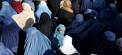 Una niña sentada en medio de una multitud de mujeres afganas que esperan recibir pan en Kabul, Afganistán; un país que oprime los derechos de las...
