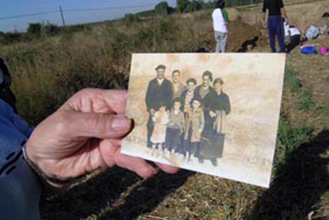 Un familiar muestra la foto de un desaparecido durante una exhumación en Berlangas de Roa, Burgos