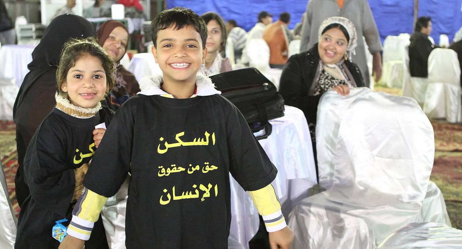 Menores egipcios llevan camisetas con la leyenda "la vivienda es un derecho humano"