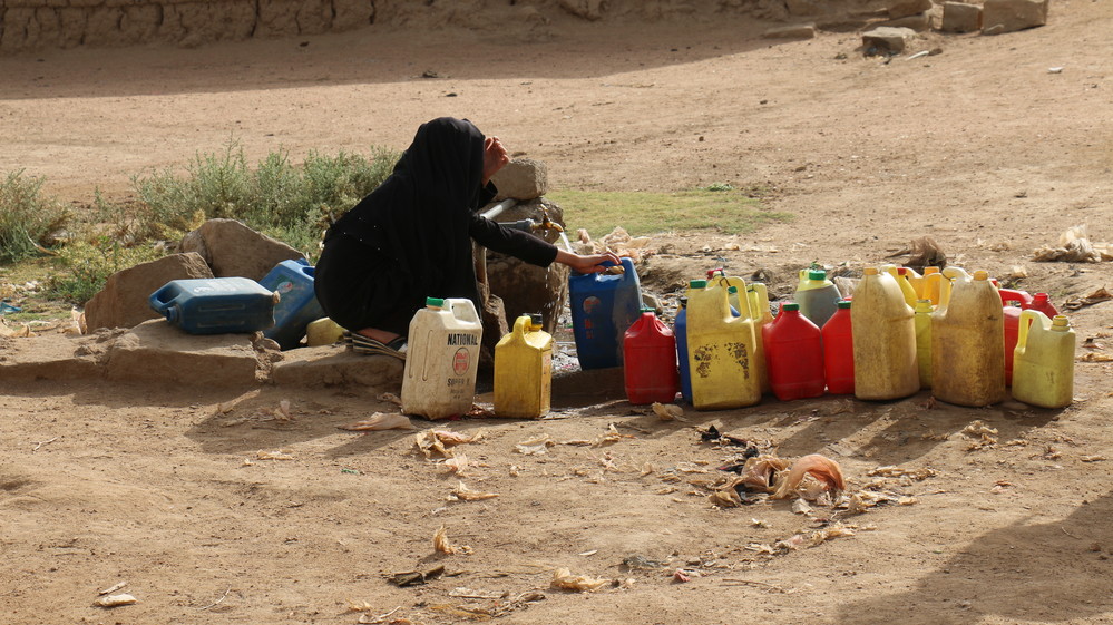 Una mujer llena varios bidones de agua en Yemen.