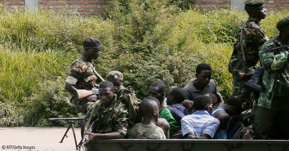 Un vehículo militar llevando soldados y hombres atados