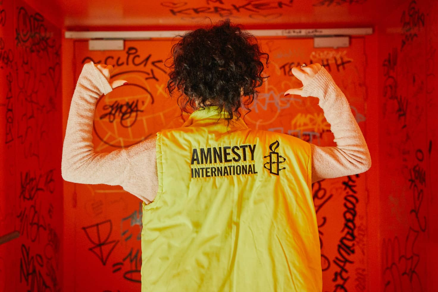 Joven de espaldas con un chaleco con el logo de Amnistía Internacional