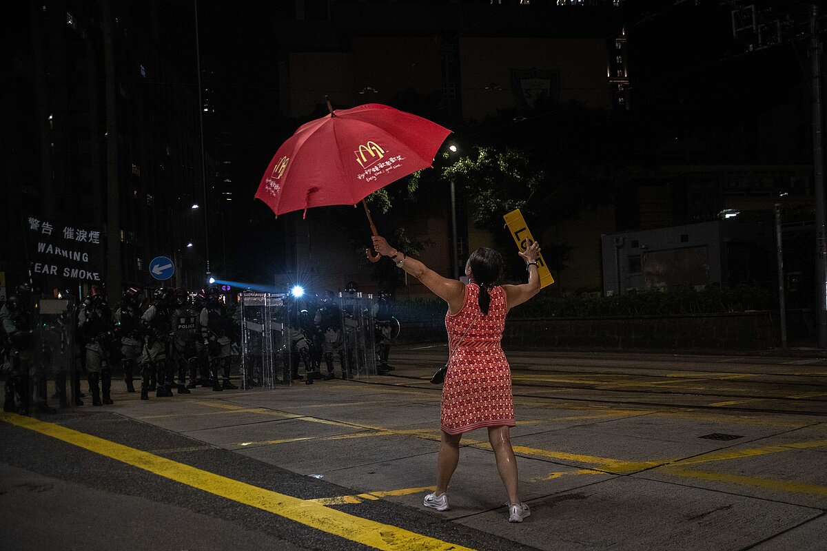 Una mujer con un paraguas y una pancarta se planta provocativamente ante la policía antidisturbios durante las manifestaciones del Día Nacional de...