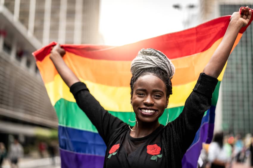 Crímenes de odio y homofobia en África. Una mujer africana sostiene una bandera arcoíris