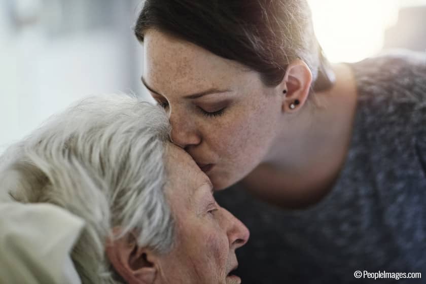 Una hija da un beso en la frente a su madre