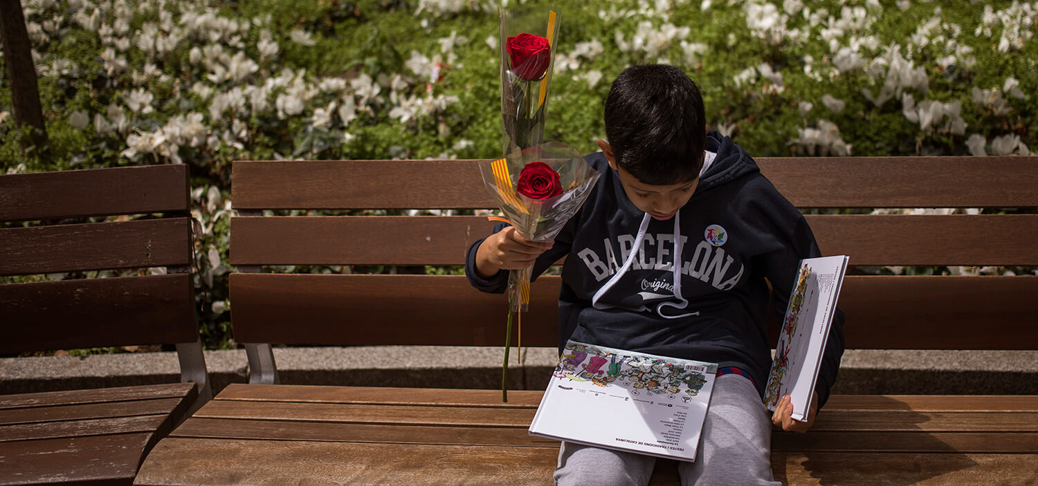 Un niño sostiene unas rosas mientras lee un libro tras comprarlo en un puesto improvisado el día de Sant Jordi, en Barcelona, ​​el 23 de abril de...