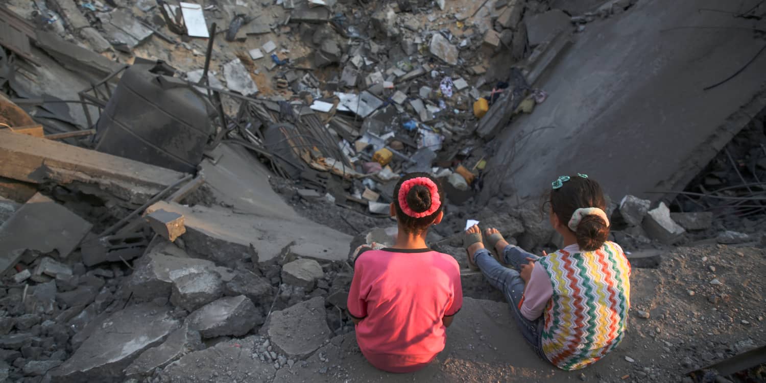 Dos niñas palestinas miran su edificio dañado en Gaza. La participación de CAF en la ampliación del tranvía a Jerusalén cuestiona derechos humanos