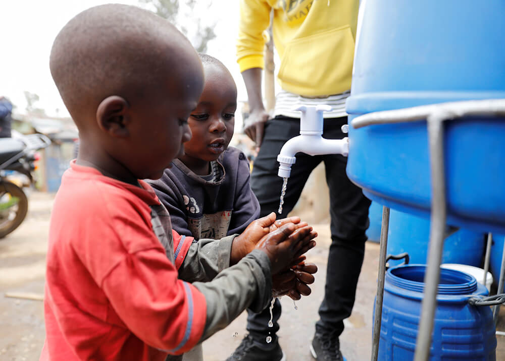 Los niños se lavan las manos en una estación de lavado de manos establecida por la organización comunitaria Shining Hope for Communities (SHOFCO)...