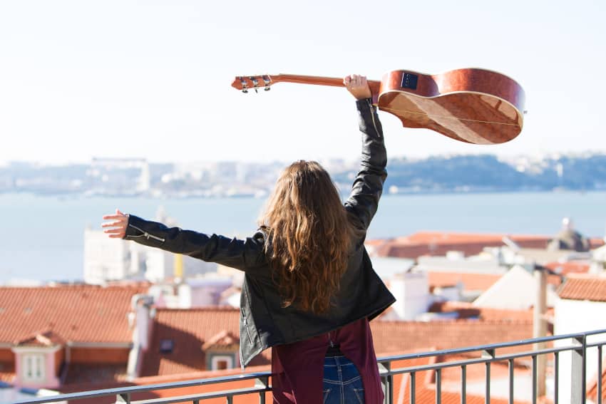 Mujer con una guitarra celebrando la libertad artística, símbolo del derecho humano a la cultura y a participar en la vida cultural.