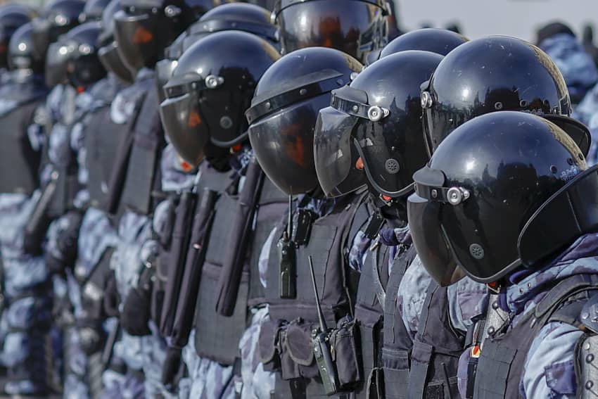Fila de policías antidisturbios con casco y escudo durante una protesta contra la guerra en Moscú, ilustrando la represión de manifestaciones...