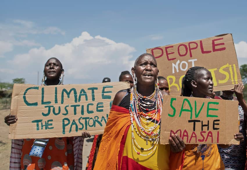 Grupo de mujeres maasai sostiene carteles de “Climate justice” y “Save the Maasai” en una marcha, visibilizando la lucha de los pueblos indígenas...