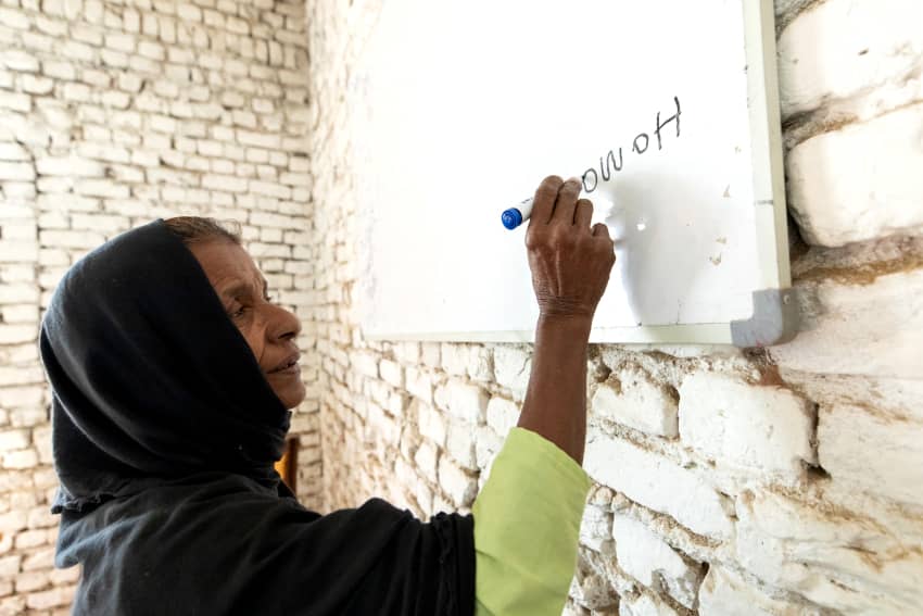 Mujer de 69 años escribe su nombre en una pizarra en un centro de alfabetización en Sindh, Pakistán, ejerciendo su derecho a la educación y al...
