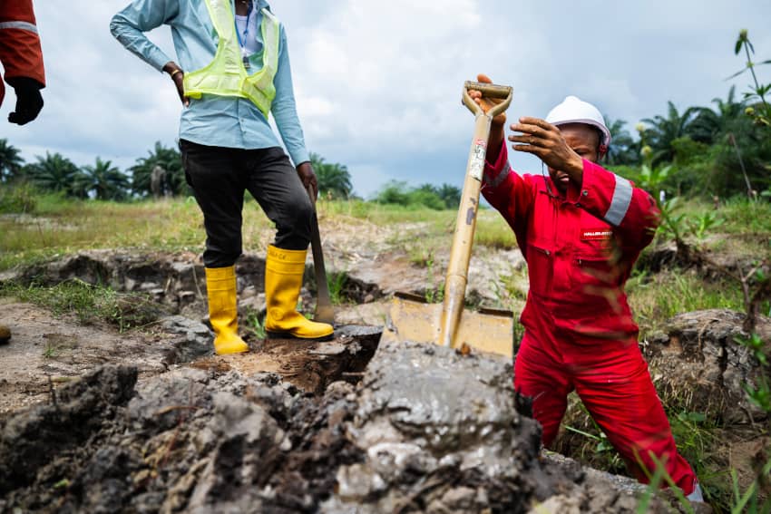 Trabajadores con equipo de seguridad revisan un terreno contaminado cerca de una instalación petrolera, reflejando el impacto de las empresas en el...