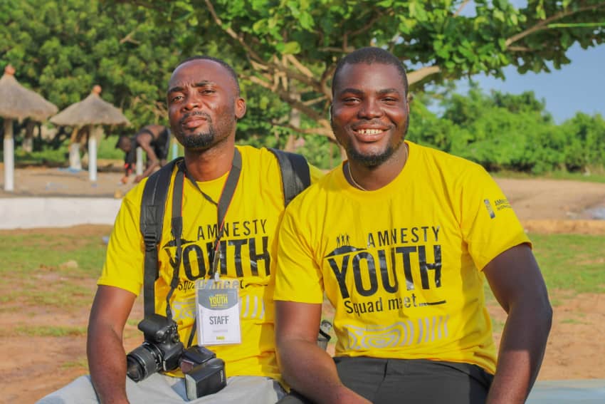 Dos jóvenes activistas de Amnistía Internacional Togo con camisetas de Amnesty Youth Squad, formados para promover derechos humanos y liderar...