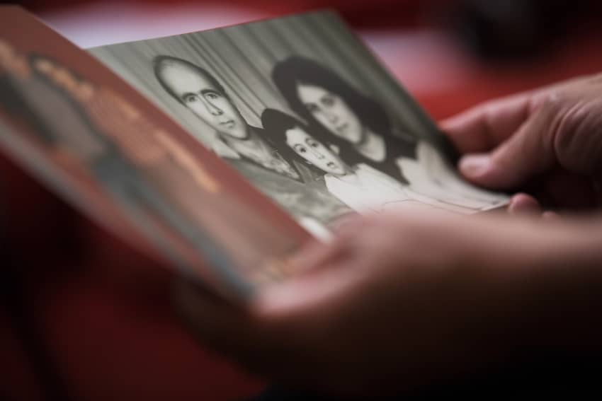 Primer plano de unas manos sujetando una foto en blanco y negro de una familia, representando la lucha contra las desapariciones forzadas y el...