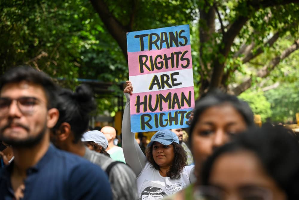 Una persona alza un cartel que recuerda que los derechos de las personas trans son derechos humanos.