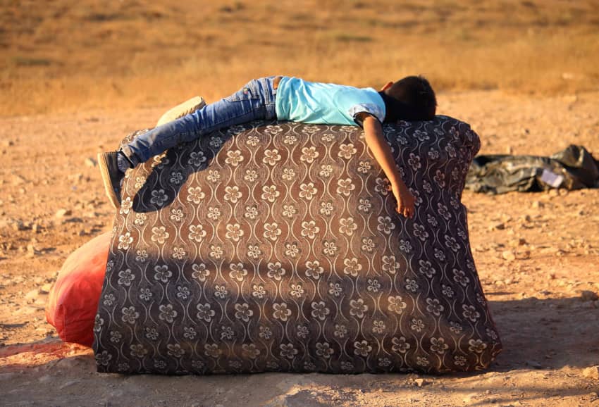 Niño refugiado sirio descansando junto a sus pertenencias