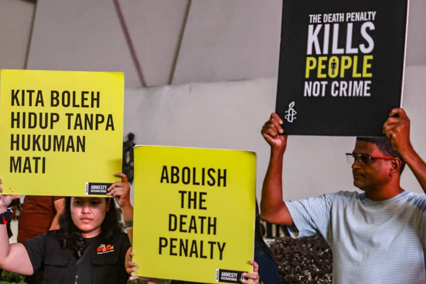 Personas sostienen carteles de Amnistía Internacional con mensajes contra la pena de muerte y a favor de su abolición total.