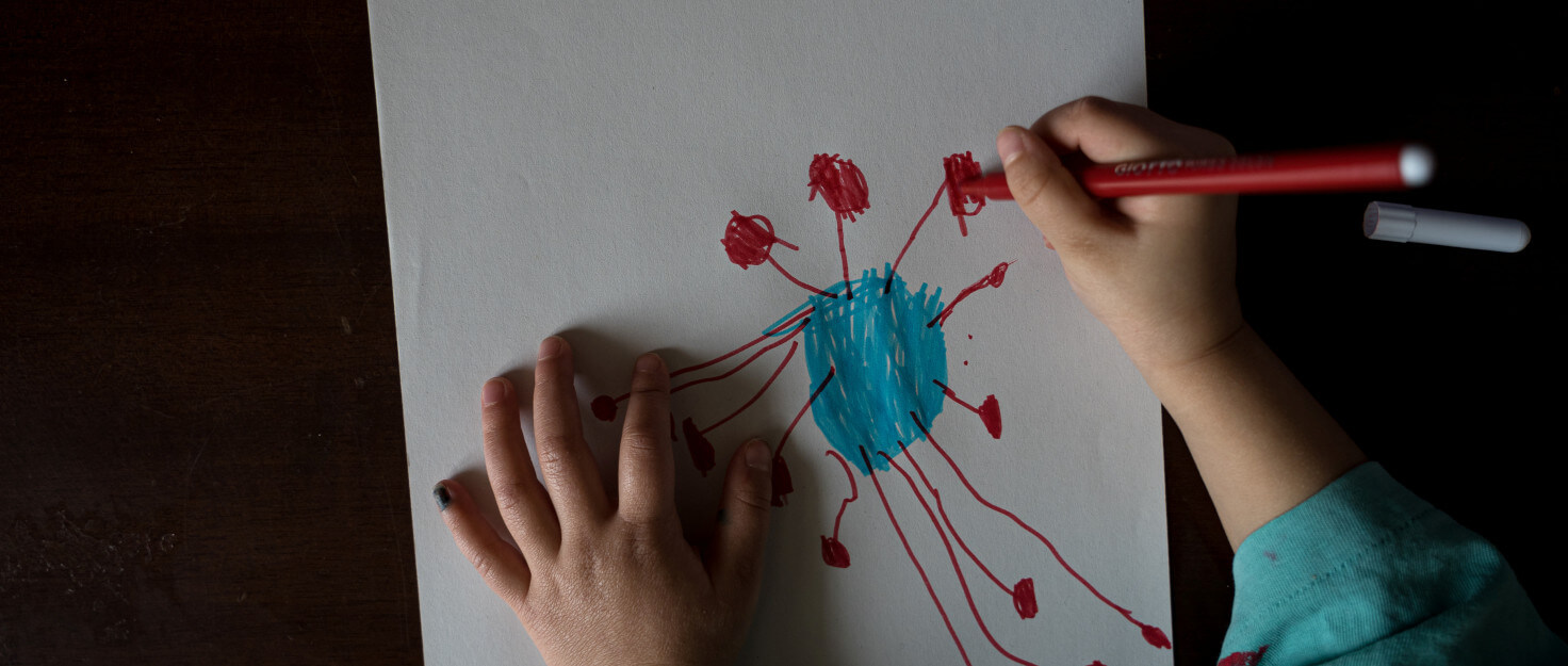 Manos de un niño dibujando un coronavirus