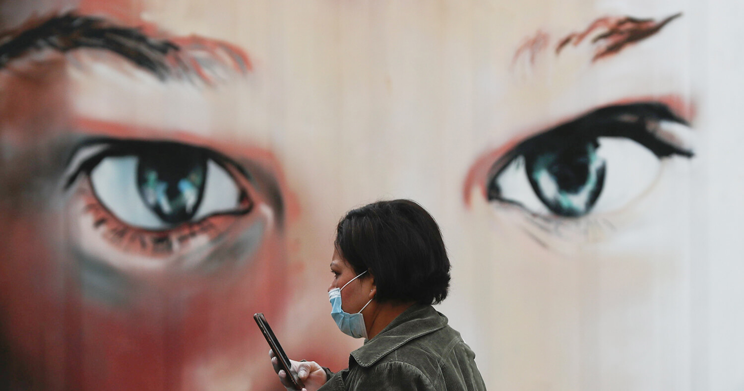 Susana Vera. Una mujer con mascarilla y guantes camina frente a un hospital en Madrid, 17 de marzo de 2020