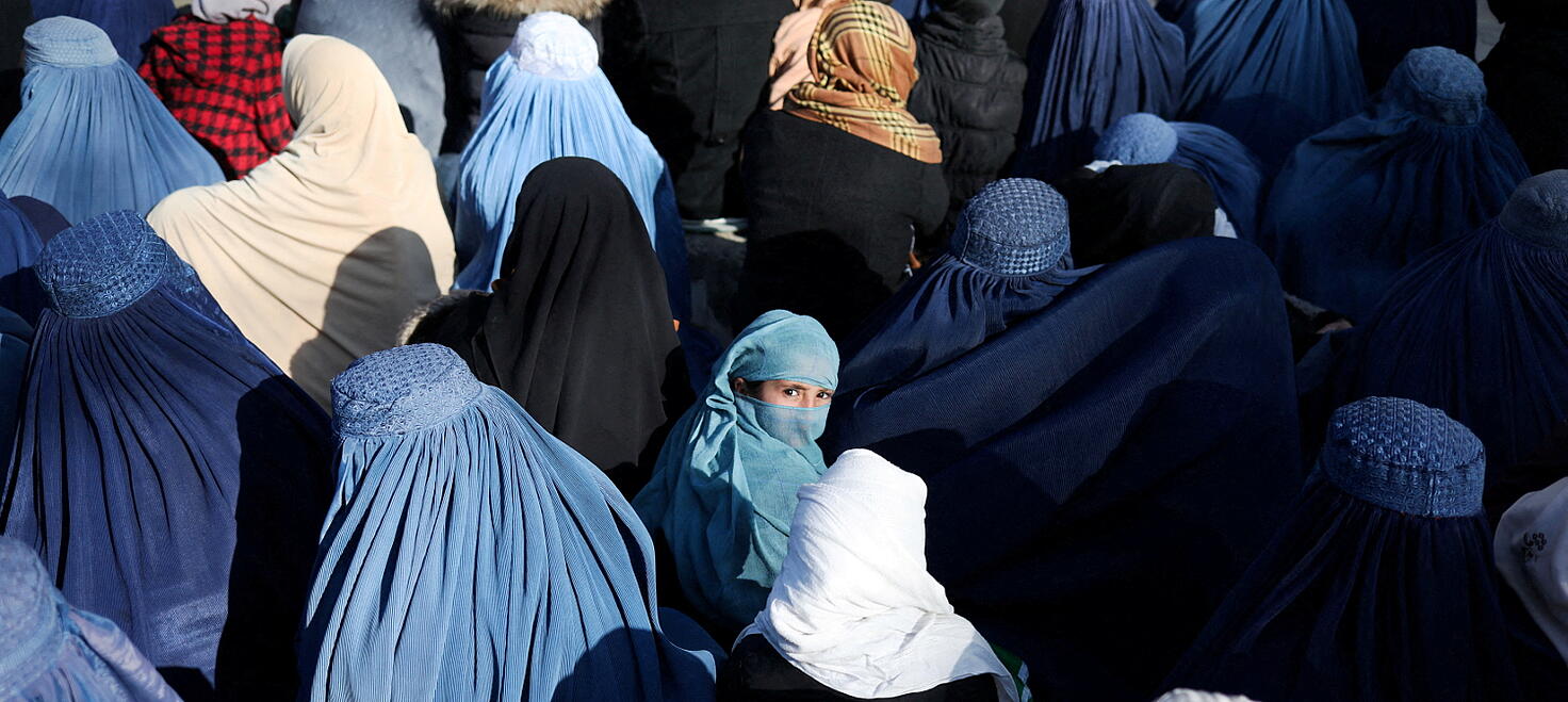 Una niña sentada en medio de una multitud de mujeres afganas que esperan recibir pan en Kabul, Afganistán; un país que oprime los derechos de las...