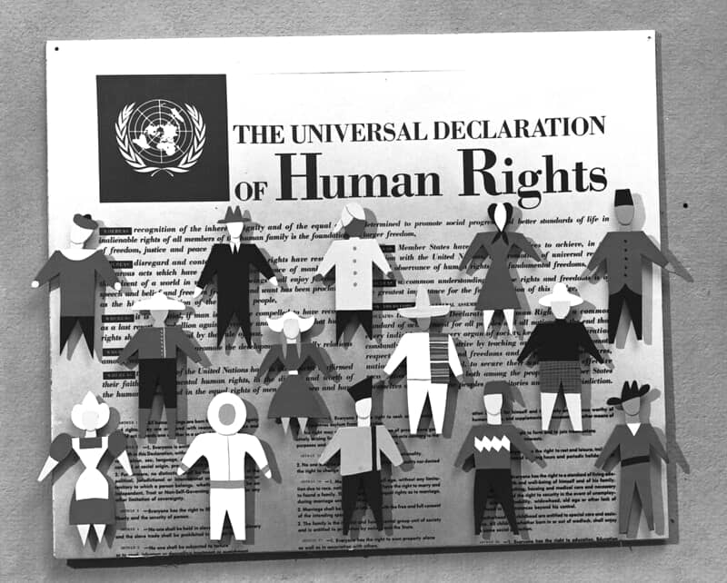 Creatividad en la que se pueden ver figuras de personas en papel sobre una declaración universal de los derechos humanos. 