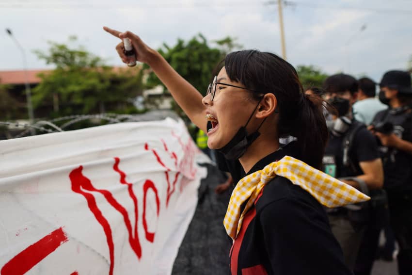Mujer gritando consignas durante una protesta mientras sostiene un espray frente a la policía