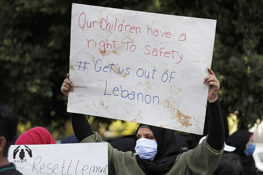Una mujer refugiada siria sostiene un cartel mientras protesta frente a la sede de la agencia de las Naciones Unidas para los refugiados, ACNUR, exigiendo ser trasladada fuera del Líbano, que está atravesando su peor crisis económica en la historia con el consiguiente aumento del desempleo y de los niveles de pobreza, 24 de septiembre de 2020.