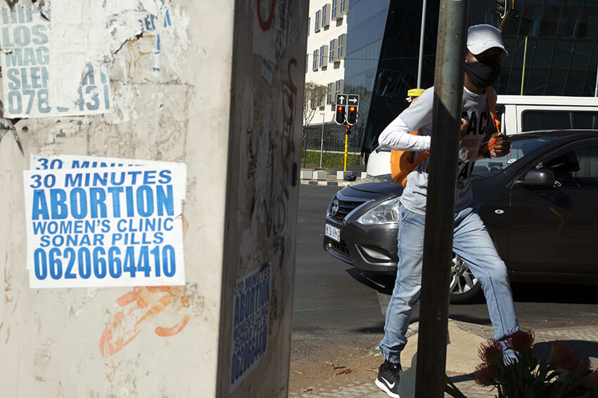 Un peatón pasa junto a un letrero pegado en una acera en Johannesburgo, Sudáfrica, el martes 18 de agosto de 2020. Millones de mujeres y niñas en todo el mundo han perdido acceso a anticonceptivos, servicios de aborto y atención relacionada debido a la pandemia del coronavirus. 