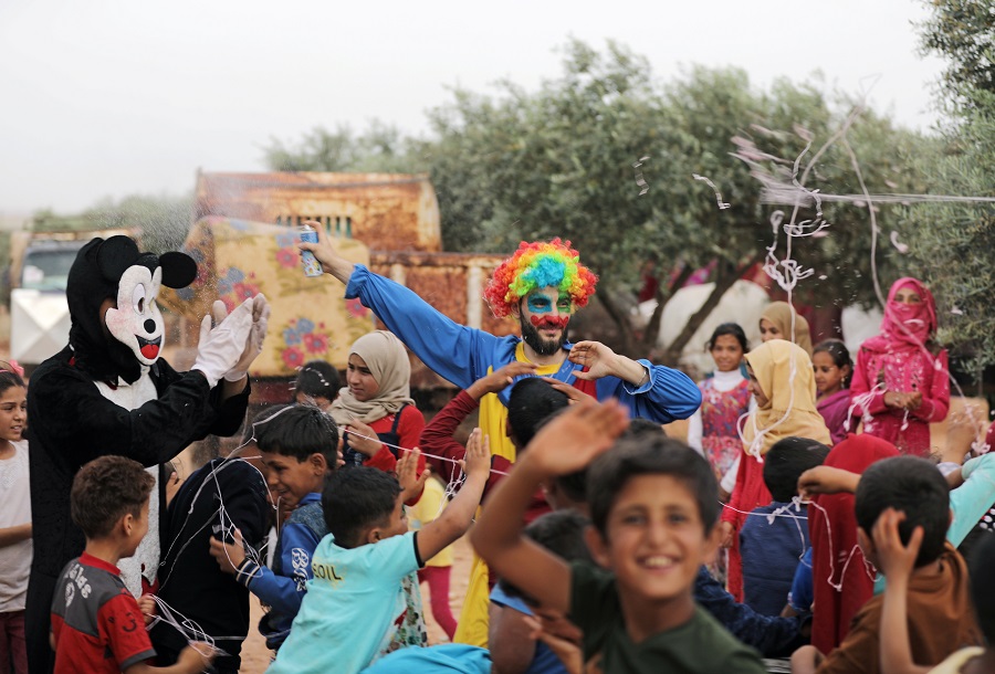 Un hombre vestido de payaso entretiene a los niños y niñas refugiadas sirias desplazadas, Idlib, Siria