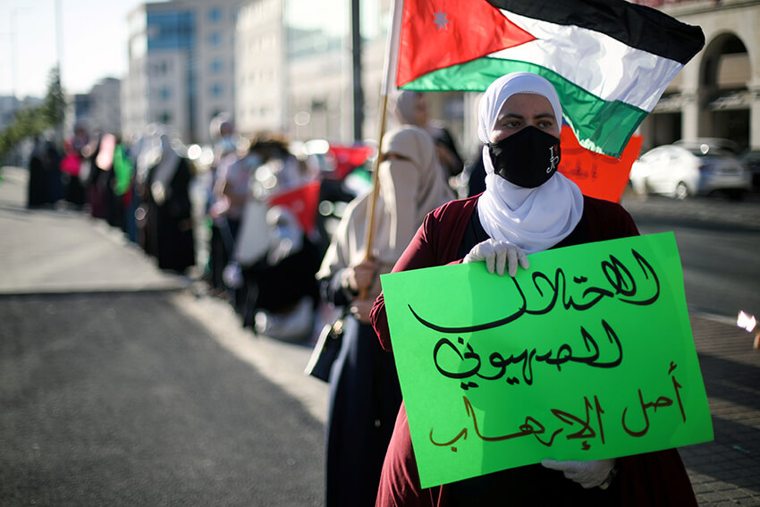Una manifestante sostiene una pancarta mientras participa en una cadena humana durante una sentada contra la anexión de partes de Cisjordania por parte de Israel, en Amman, Jordania, el 27 de junio de 2020. La pancarta dice: "La ocupación sionista es la raíz del terrorismo"