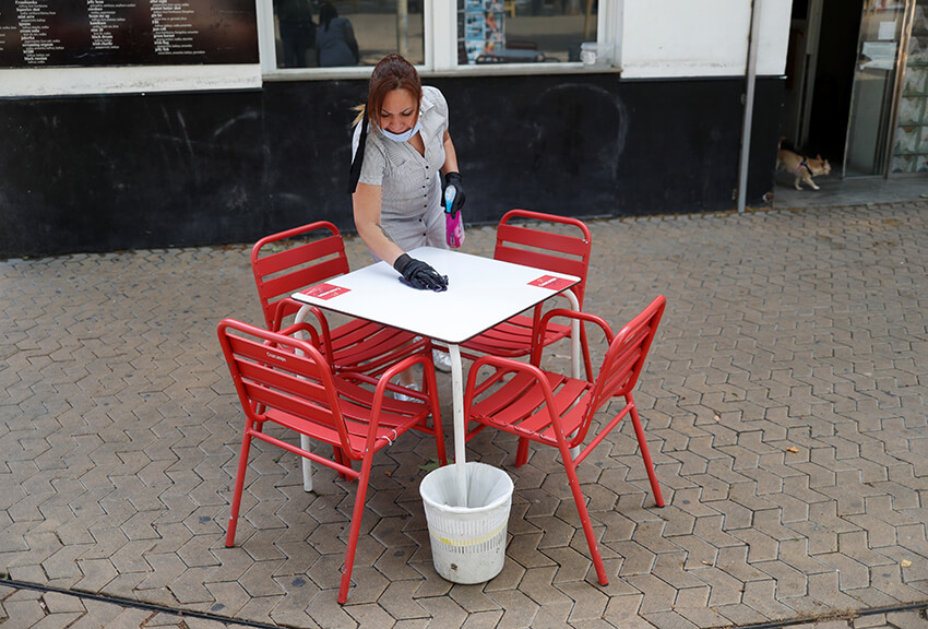 Una mujer limpia una mesa fuera de un bar